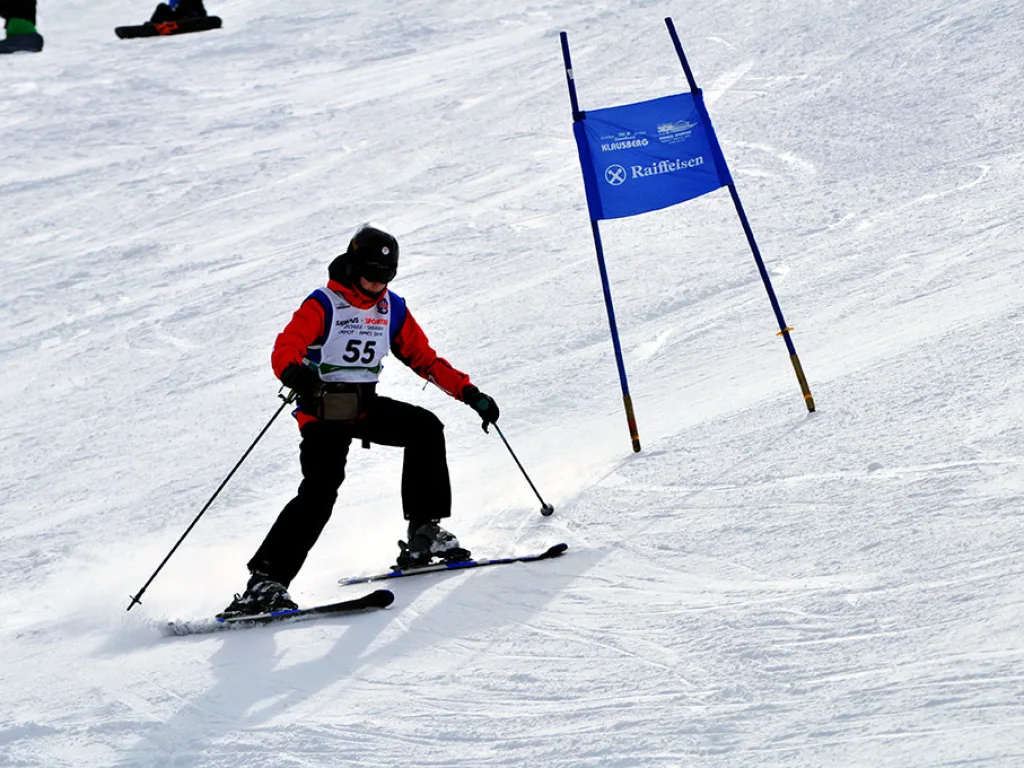 Skifahrerin mit Startnummer 55 zieht eine Kurve.